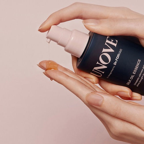 UNOVE Silk Oil Essence 70ml in clear beige-tinted pump bottle, glossy liquid inside, styled on a clean neutral surface