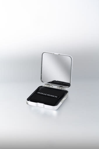 A compact with a built-in mirror and puff, labeled 'Muzigae Mansion', designed for facial blotting with oil paper sheets.